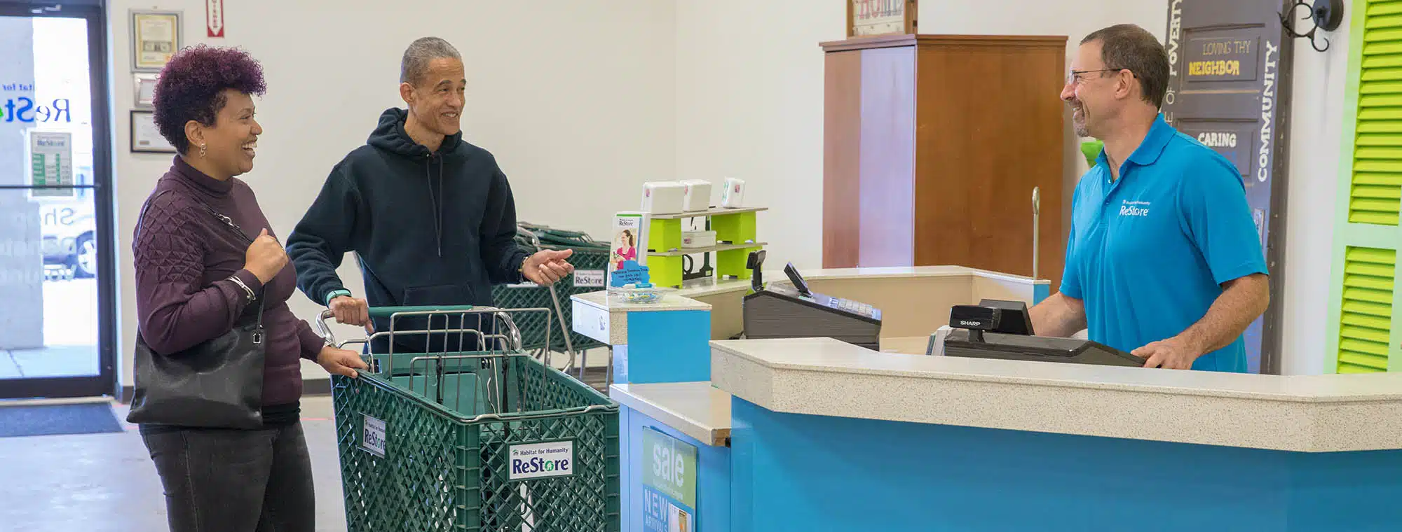 Customers with shopping cart talking to cashier